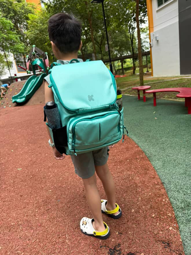 Child wearing a teal backpack on a playground