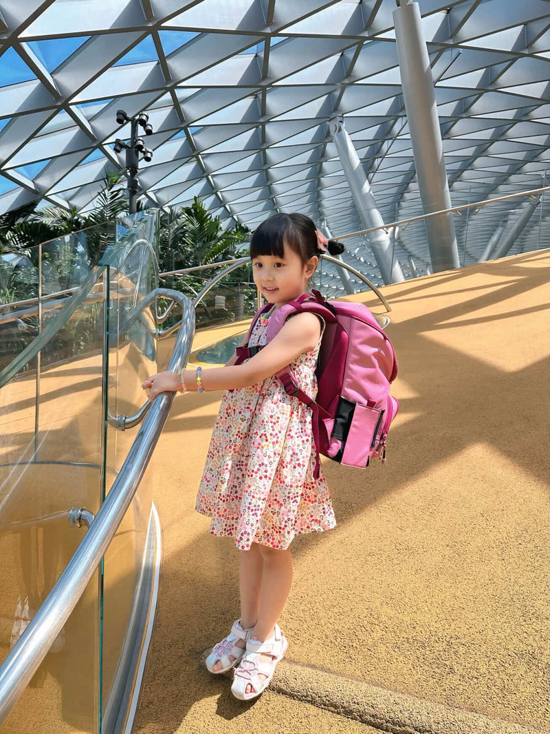 Child in a floral dress with a pink backpack standing inside the flower dome in Singapore