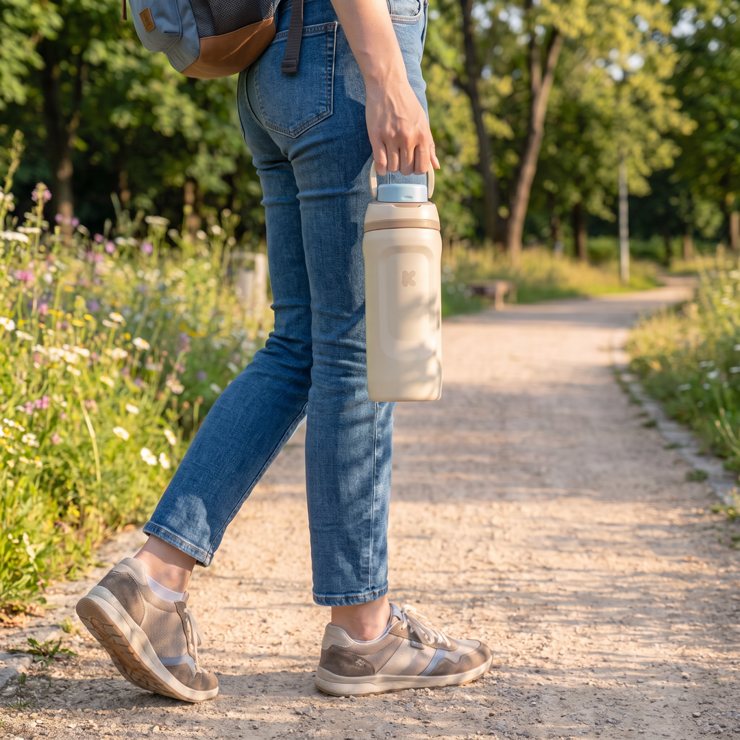 Lady holding a beige water bottle during an outdoor walk.
