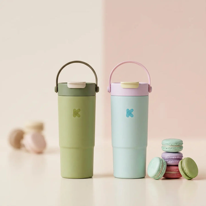 A green and blue water bottle in a studio setup with pastel themed backdrop and macaroons.