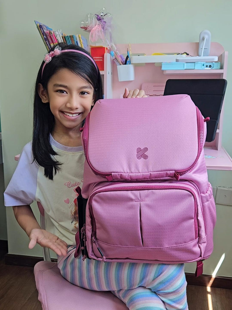 Child with a pink backpack in a room with a desk and stationery.